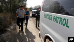 FILE - U.S. Border Patrol agents pick up immigrants suspected of crossing into the United States illegally along the Rio Grande near Granjeno, Texas, Aug. 11, 2017.