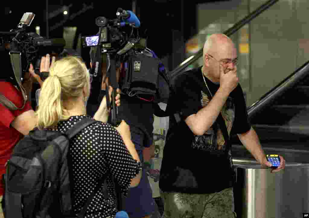 A relative walks past members of the press as he arrives at Schiphol airport in Amsterdam, the Netherlands.
