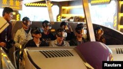 Staff members wearing virtual reality goggles sit in a motorized cart while performing an inspection of the attraction "Fly Over Guizhou," at the Oriental Science Fiction Valley theme park in Guiyang, Guizhou province, China, Nov. 16, 2017. 
