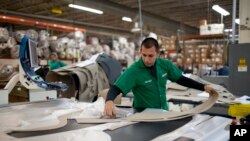 FILE - A worker manufactures car dash mats at a factory belonging to the TECMA group in Ciudad Juarez, Mexico, Dec. 27, 2013.