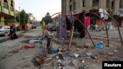 A woman walks past the site of a car bomb attack at Palestine Street in Baghdad, Nov. 2, 2014. 