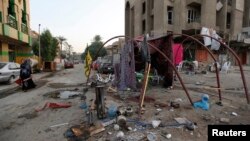 A woman walks past the site of a car bomb attack at Palestine Street in Baghdad, Nov. 2, 2014. 