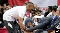 Houston Rockets guard Russell Westbrook, left, grabs at James Harden as they joke around at the bench during the second half of an NBA basketball preseason game against the Shanghai Sharks, Monday, Sept. 30, 2019, in Houston. 