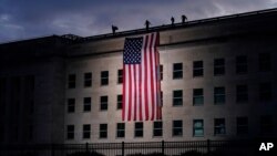 A large American flag is unfurled at the Pentagon ahead of ceremonies at the National 9/11 Pentagon Memorial to honor the 184 people killed in the 2001 terrorist attack on the Pentagon, in Washington, Friday Sept. 11, 2020. (AP Photo/J. Scott…