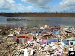 FILE - A Haitian migrant walks among the ruins of a neighborhood destroyed by Hurricane Dorian in Sandbank, Abaco, Bahamas, Sept. 28, 2019.