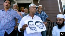 Seorang anggota masjid Al-Furqan Jame di Ozone Park, Queens, New York memegang gambar sketsa tersangka penembak Imam Maulama Akonjee dan Thara Uddin yang disebarkan oleh pihak kepolisisan setempat (14/8). (AP/Craig Ruttle)