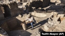 Avshalom Davidesko from the Israel's Antiquities Authority examines a jar in a massive ancient winemaking complex dating back some 1,500 years in Yavne, south of Tel Aviv, Israel, Monday, Oct. 11, 2021. (AP Photo/Tsafrir Abayov)