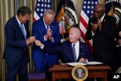조 바이든(왼쪽 두번째) 미국 대통령이 16일 백악관에서 '인플레이션 감축 법안'에 서명한 직후 펜을 조 맨친 상원의원에게 건네고 있다. 왼쪽부터 맨친 의원, 척 슈머 상원 민주당 대표, 바이든 대통령, 짐 클라이번 하원 민주당 원내 총무.