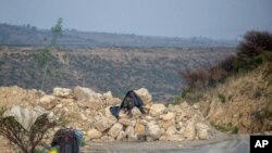 FILE - An Ethiopian government soldier mans a position where rocks have been placed to create a narrowing in a road leading to Abi Adi, in the Tigray region of northern Ethiopia, May 11, 2021.
