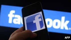 This illustration photo shows the Facebook logo on a smartphone in front of a computer screen in Los Angeles on August 12, 2021. (Photo by Chris DELMAS / AFP)