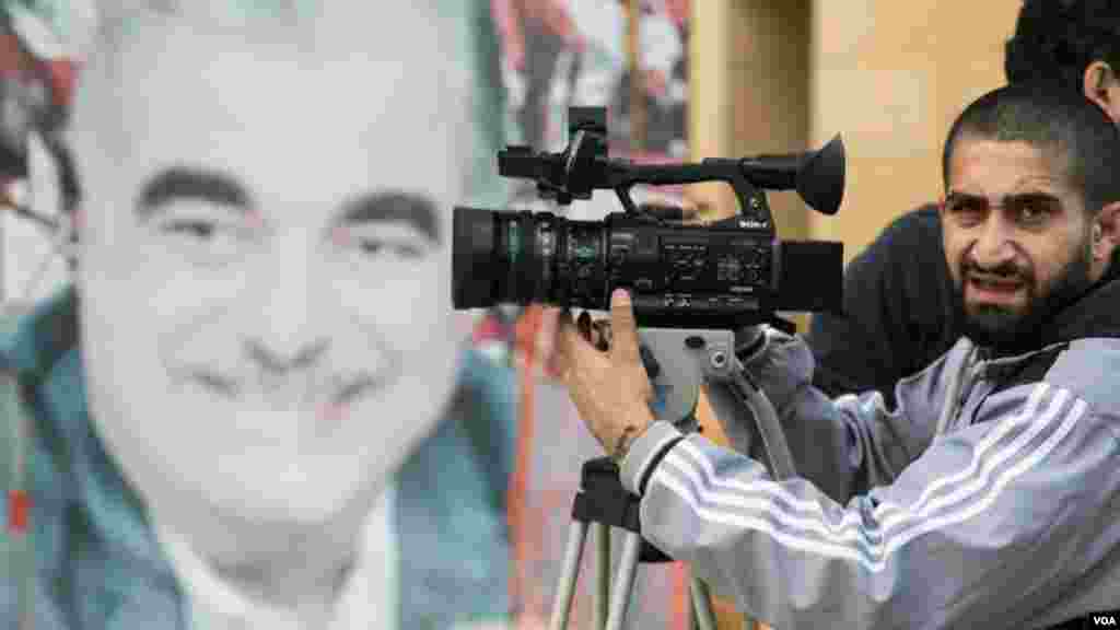 A photographer takes pictures during a parade marking Independence Day, Beirut, Lebanon, Nov. 22, 2017. In the background is a photo of Prime Minister Saad Hariri&#39;s father, Rafik, who was killed in a car bomb in 2005. He was previously prime minister. (John Owens for VOA)