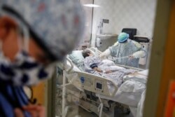 FILE - Resident physician Leslie Bottrell stands outside a room at an Intensive Care Unit as a nurse suctions the lungs of a COVID-19 patient, April 20, 2020, at St. Joseph's Hospital in Yonkers, New York.