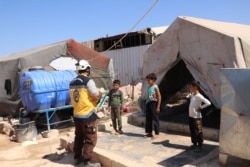 White Helmets, a Syrian aid group, instruct children in the camps on how to wash their hands to protect them from the coronavirus, in Idlib, Syria, July 24, 2020.