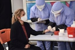 FILE - Health care workers conduct a blood test on Bolivia's Interim President Jeanine Anez at the presidential palace in La Paz, Bolivia, June 12, 2020.