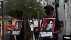 បុរសម្នាក់កាន់បដាដែលមានរូបអ្នកស្រី Aung San Suu Kyi នៅពេលចូលរួមបាតុកម្មទាមទារឲ្យមានការដោះលែងអ្នកស្រីនិងមេដឹកនាំស៊ីវិលដទៃទៀត ក្នុងទីក្រុងរ៉ង់ហ្គូន ប្រទេសមីយ៉ាន់ម៉ា កាលពីថ្ងៃទី១៥ ខែកុម្ភៈ ឆ្នាំ២០២១។