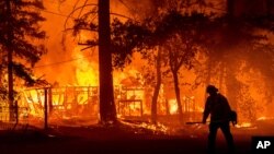 Seorang petugas damkar melewati kobaran api dari kebakaran hutan "Dixie Fire" di Plumas County, California (24/7). 