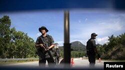 FILE - Members of the General Operations Force control the checkpoint on the road near an area where an abandoned human trafficking camp was discovered in northern Malaysia, May 28, 2015.