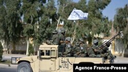 Pasukan Taliban dari Korps Militer Al-Badr duduk di atas kendaraan bersenjata dalam sebuah parade di Kandahar, Afghanistan, pada 8 November 2021. (Foto: AFP/Javeed Tanveer)