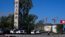 FILE - A woman walks by an Evergrande new housing development in Beijing, China, Sept. 22, 2021. 
