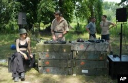 A DJ holds a techno performance while young volunteers clear debris from a building destroyed by a Russian rocket in the village of Yahidne, Chernihiv Region, Ukraine, Sunday, July 24, 2022