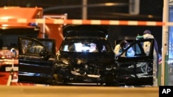Forensic technicians work on a damaged car sitting with its doors open after a driver plowed into a busy Christmas market in Magdeburg, Germany, Dec. 21, 2024.