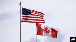In this photo taken Sunday, May 17, 2020, U.S. and Canadian flags fly atop the Peace Arch at Peace Arch Historical State Park on the border with Canada, where people can walk freely between the two countries at an otherwise closed border, in Blaine,…