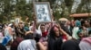 FILE - Relatives mourn as they lift portraits of family members they lost in the collapse of a mountain of trash at a garbage dump, during a funeral service held at Gebrekristos church in Addis Ababa, Ethiopia, March 13, 2017.