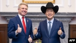 This handout picture taken and released by the Taiwan Presidential Office on May 27, 2024 shows Taiwan's President Lai Ching-te, right, posing with a hat received from U.S. Representative Michael McCaul, left, during a meeting at the Presidential Office in Taipei.