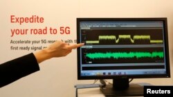 An exhibitor points to a screen displaying 5G spectrums during the Mobile World Congress in Barcelona March 5, 2015.