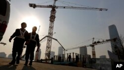 FILE - Workers walk out from a construction site at the Central Business District of Beijing, China, Jan. 20, 2015.