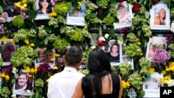 People stand near a makeshift memorial outside St. Joseph Catholic Church near the Champlain Towers South residential condo, June 29, 2021, in Surfside, Fla.