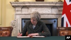 Britain's Prime Minister Theresa May signs the official letter to European Council President Donald Tusk, in 10 Downing Street, London, March 28, 2017, invoking Article 50 of the bloc's key treaty, the formal start of exit negotiations. Britons voted in June to leave the bloc after four decades of membership. 