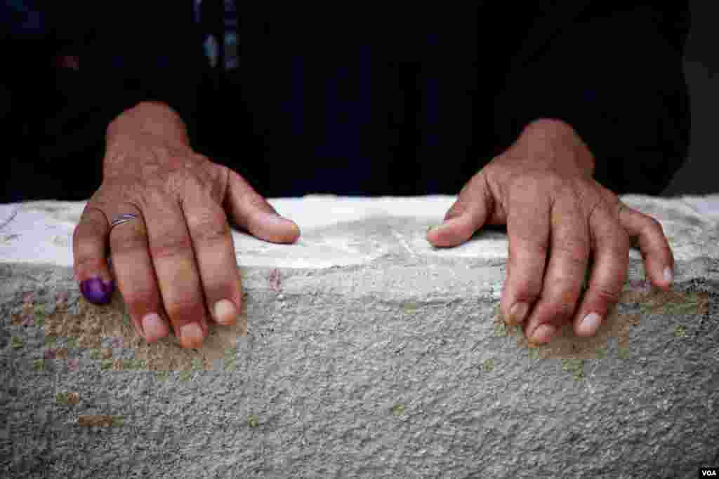 A woman displays her inked finger, showing that she has already voted. (Y. Weeks/VOA)