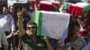 Palestinians carry flag-covered coffins containing the remains of Palestinian militants