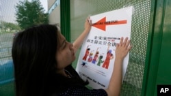 FILE - Ailu Xu, a graduate student from China, posts a sign directing Chinese students to new student orientation at the University of Texas at Dallas in Richardson, Texas, Aug. 22, 2015. 