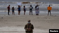 រូបឯកសារ៖ មន្រ្តី​ប៉ូលិស​ម្នាក់ បាន​ដើរ​ចេញពី​អ្នកស្រុក​ក្នុង​តំបន់ ដែល​តវ៉ា​ប្រឆាំងនឹង​ការបិទ​ឆ្នេរសមុទ្រ​នៅ​ថ្ងៃទី៤ ខែកក្កដា ចំ​ពេល​មាន​ការផ្ទុះឡើង​នៃ​ជំងឺកូវីដ​១៩ នៅ​ទីក្រុង Galveston រដ្ឋ Texas នៅ​ថ្ងៃទី៤ ខែកក្កដា ឆ្នាំ ២០២០។