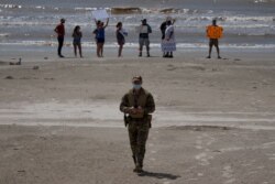 A police officer walks away from local residents protesting closed beaches on the 4th of July amid the coronavirus pandemic, in Galveston, Texas, July 4, 2020.