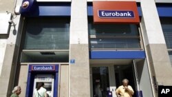 A woman makes a transaction at an ATM of a Eurobank branch in Athens September 23, 2011.
