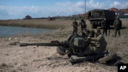 FILE - Ukrainian servicemen deploy a weapon at the beach of the Azov Sea in Shyrokyne, eastern Ukraine, April 15, 2015. 