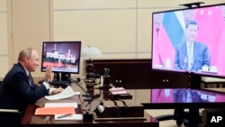 Russian President Vladimir Putin gestures during his videoconference with Chinese President Xi Jinping, right on the screen, in Moscow, Russia, Wednesday, Dec. 15, 2021. (Mikhail Metzel, Sputnik, Kremlin Pool Photo via AP)