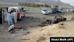 Des bénévoles se tiennent devant un véhicule où se trouvait mollah Akhtar Mansour, dans la région de Baluchistan, une province du Pakistan, près de la frontière de l'Afghanistan, le 21 mai 2016.