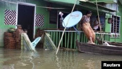 A woman tries to get on a boat from her house half-submerged in Daga township, Ayeyarwaddy division, about 126 kilometers (78 miles) northwest of Rangoon, Burma, August 24, 2012.