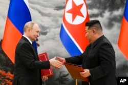 Ruski predsjednik Vladimir Putin (lijevo) i sjevernokorejski lider Kim Džong Un razmjenjuju dokumente tokom ceremonije potpisivanja novog partnerstva u Pjongjangu, Sjeverna Koreja, 19. juna 2024. (Kristina Kormilitsyna, Sputnjik, Kremlj Pool Fotografija preko AP)