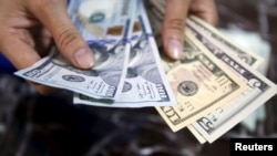 បុគ្គលិក​ម្នាក់​ពិនិត្យ​មើល​ក្រដាស​ដុល្លារ​អាមេរិក​នៅ​ធនាគារ​មួយ​នៅ​ក្នុង​ក្រុង​ហាណូយ ប្រទេស​វៀតណាម កាលពី​ថ្ងៃទី១២ ខែសីហា ឆ្នាំ២០១៥។