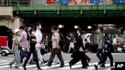 Warga mengenakan masker untuk menghindari penyebaran virus corona, saat menyebrangi jalan di ibu kota Tokyo, Jepang, 10 Juli 2020.