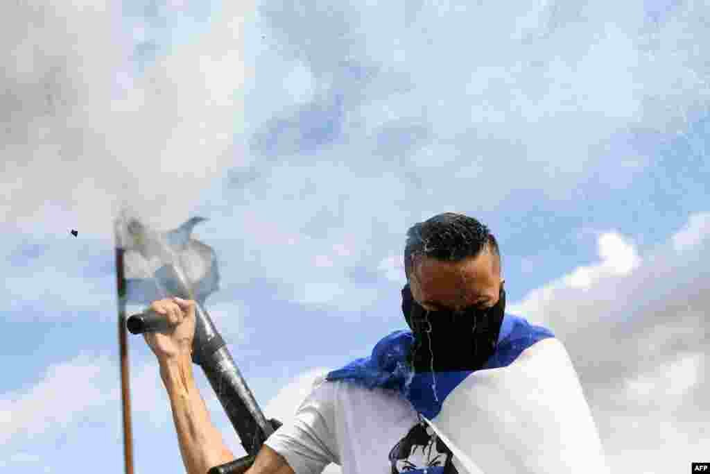 An anti-government demonstrator fires a homemade mortar in Managua, Nicaragua demanding justice for the death of six members of a single family who died when their house was burnt.