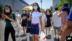 Orang-orang memakai masker untuk melindungi dari virus corona saat mereka berjalan di Beijing, Jumat, 5 Juni 2020. (Foto: AP)
