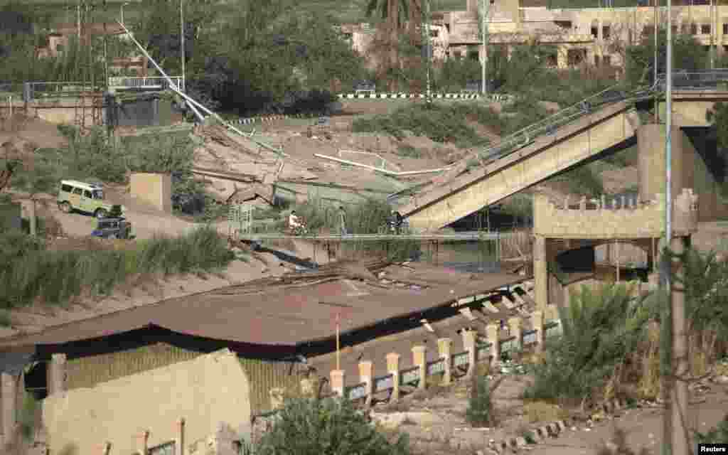 Warga menyeberangi jembatan darurat setelah jembatan sebelumnya hancur karena ledakan bom di Deir al-Zor, Suriah (20/7).