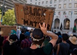 Supporters of Black Lives Matter hold signs during a protest outside the Hall of Justice as they demonstrate against the death of George Floyd, in Los Angeles, California, on June 10, 2020.