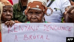 Mmoja wa wapigania uhuru akiwa na mavazi ya kiasili amebeba bango wakati wa maandamano kupinga ziara ya Mfalme wa Uingereza Charles III.